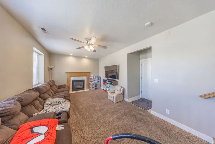 Carpeted living area featuring a fireplace with a wood mantle, recessed lighting, and a ceiling fan
