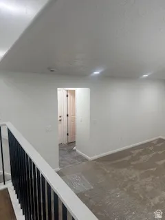 Open interior space featuring white walls, recessed ceiling lighting, and a contemporary black metal baluster railing