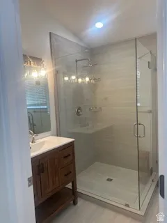Contemporary bathroom featuring a spacious glass-enclosed shower, a wood-finish vanity with a white countertop and integrated sink, and recessed ceiling lighting