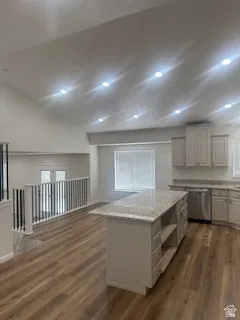 Kitchen featuring an island with stone countertop, wood-finish flooring, recessed lighting, white cabinetry, and stainless steel dishwasher