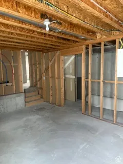 Unfinished basement space featuring exposed wood framing, concrete foundation walls, and a concrete floor