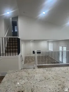 Open-concept living space featuring a spacious granite countertop, vaulted ceilings with recessed lighting, and a modern metal spindle railing system