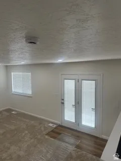 White double doors with integrated blinds, recessed lighting, wood-finish flooring, and a textured ceiling