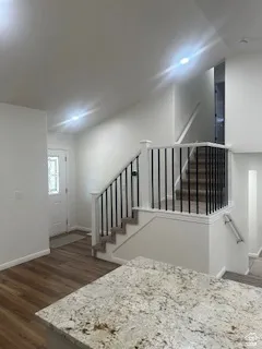 Split-level entry with wood-finish flooring, white walls, and recessed lighting