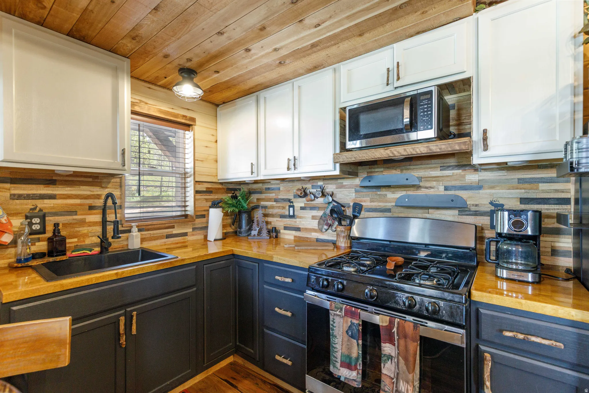 Kitchen featuring butcher block countertops, a gas range with stainless steel elements, and a mosaic tile backsplash