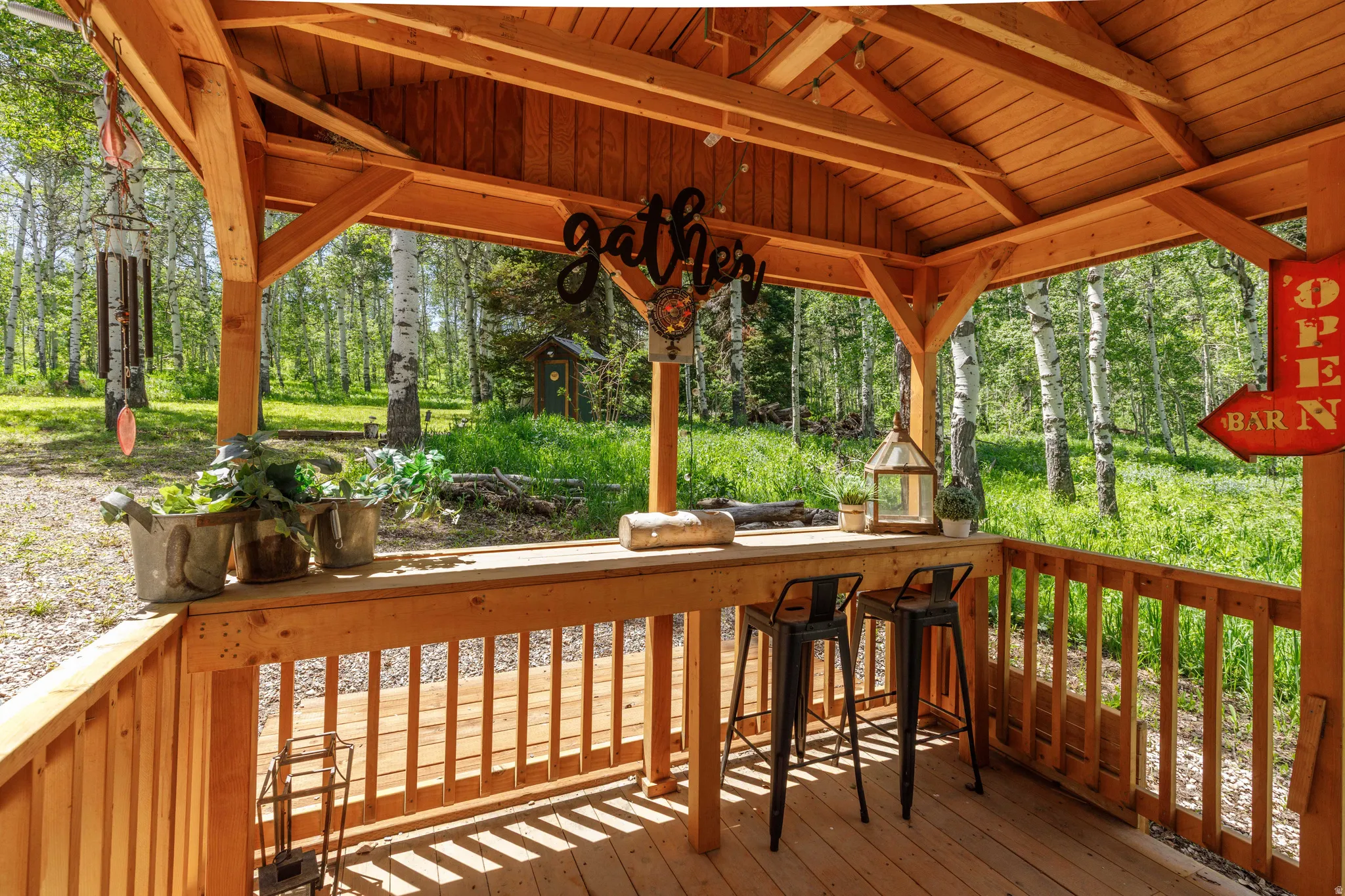 Exposed wood beam gazebo featuring a built-in bar, wood-finish flooring, and slatted wood railings