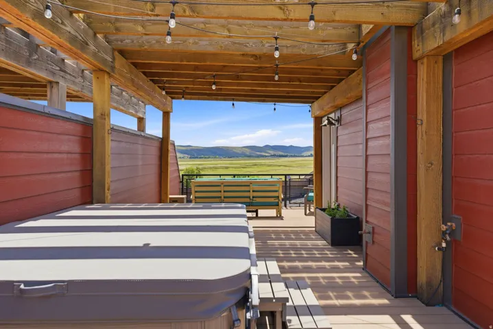 Covered outdoor deck with a private hot tub and string lighting