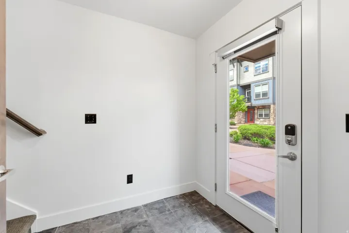 Entryway featuring dark tile flooring and white trim