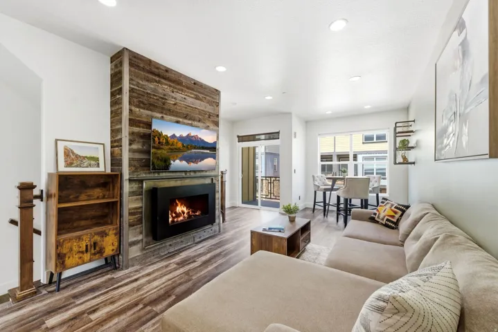 Living area featuring a modern fireplace with a wood-finish accent wall, wood-finish flooring, and recessed lighting