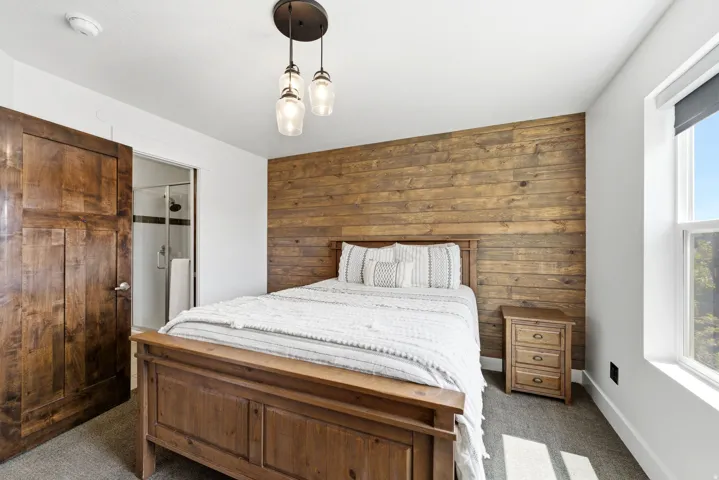 Bedroom featuring a wood-panel accent wall, recessed lighting, and a large window
