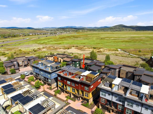 Modern multi-level townhome featuring a rooftop deck with wood pergola, solar panels, and a painted exterior