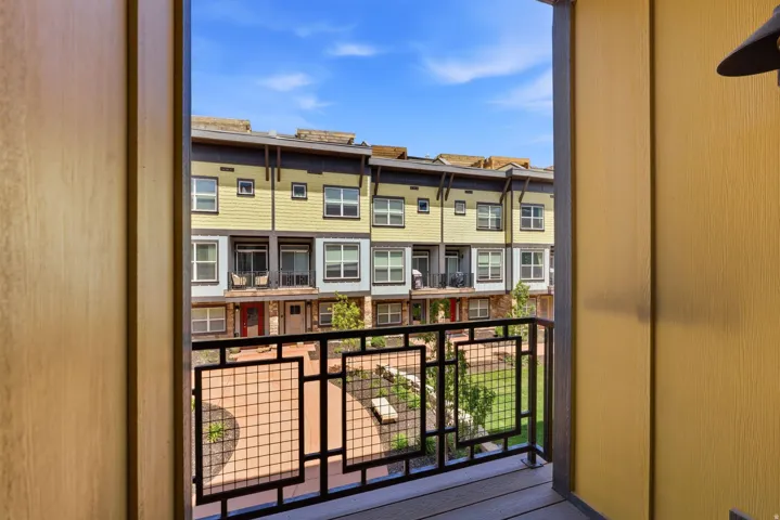 Balcony featuring metal railings, wood-look flooring, and a contemporary wall light fixture