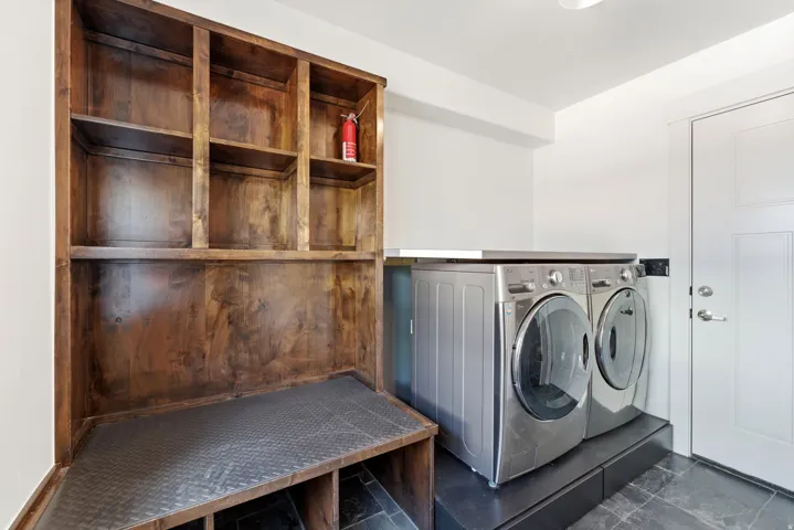 Dedicated laundry space featuring a built-in wood-finish storage unit with shelving, diamond plate bench, and cubbies