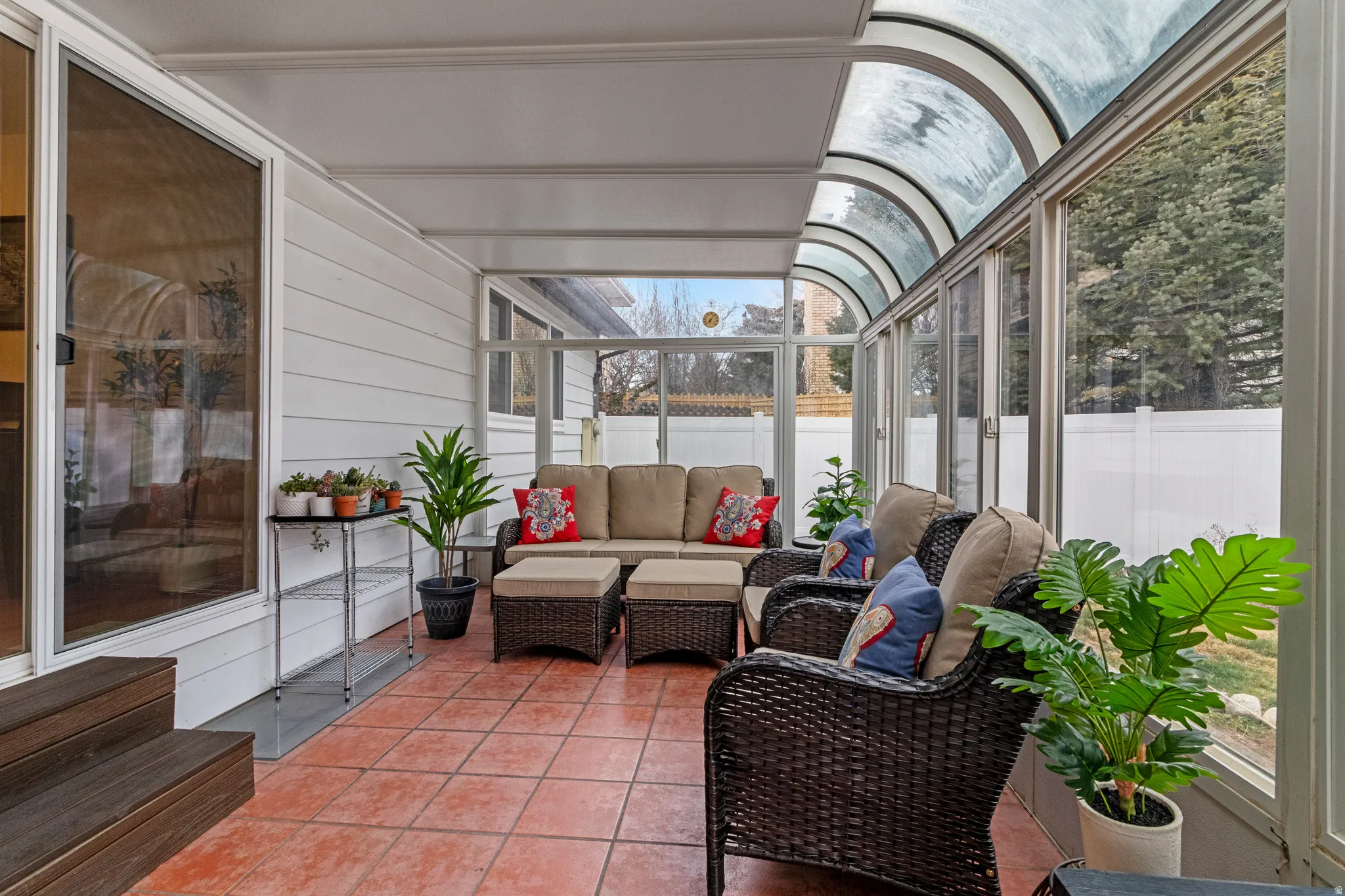 Enclosed sunroom featuring a vaulted glass ceiling, full-length windows, and terra cotta tile flooring