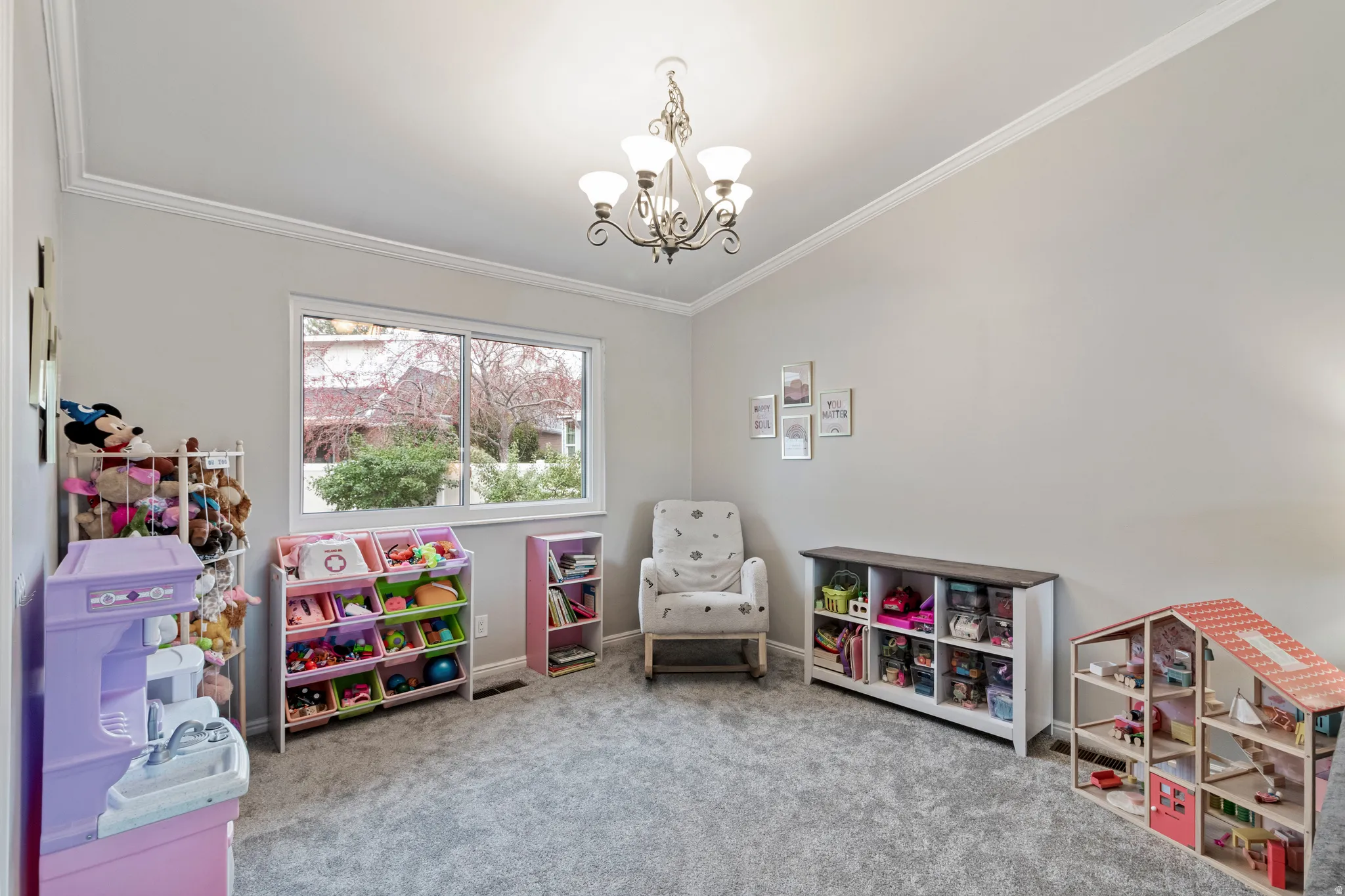 Bright room featuring a large window, crown molding, and a five-light chandelier