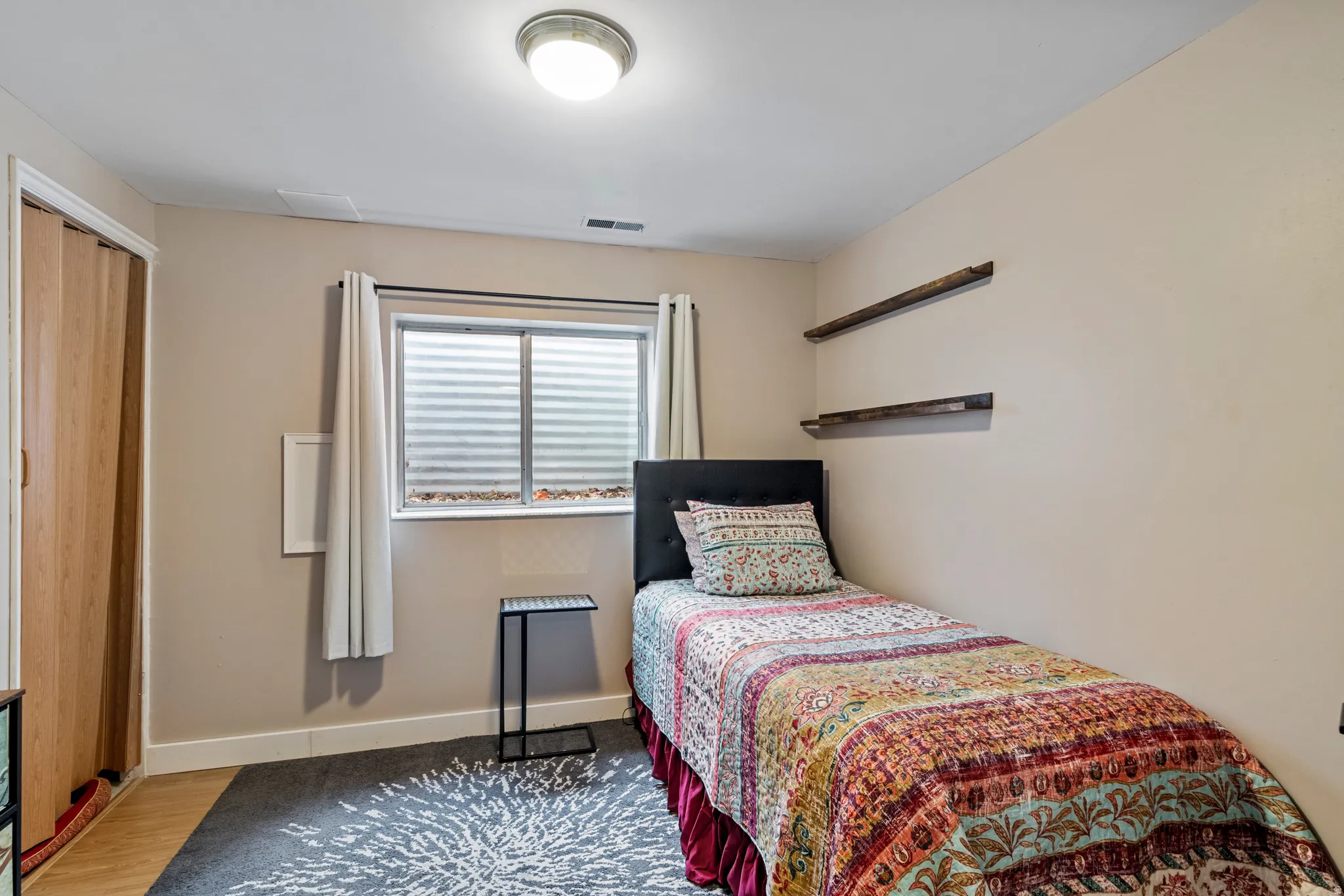 Room featuring light-toned walls, a window with horizontal blinds, and a built-in light fixture