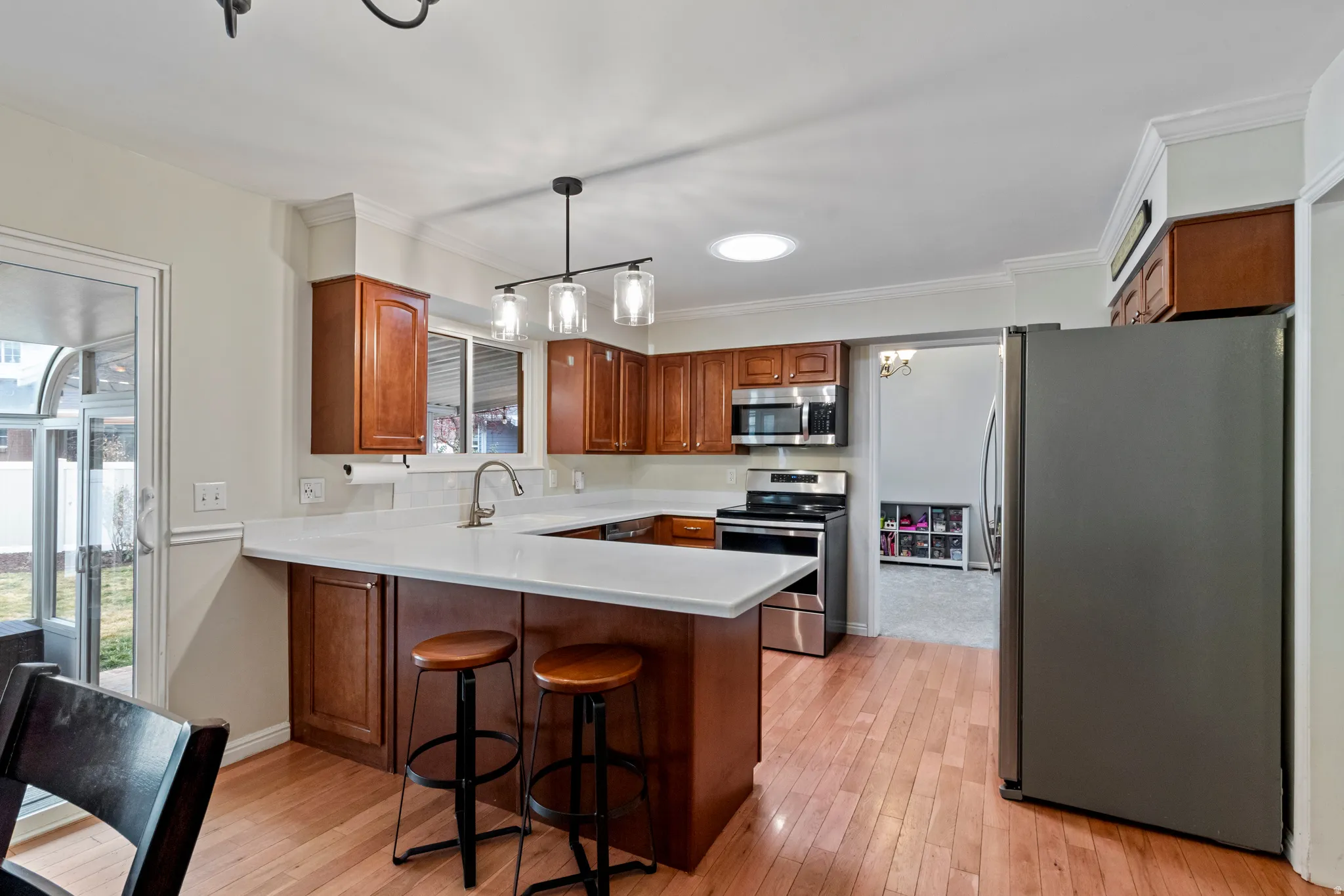 Kitchen featuring wood-finish flooring, a U-shaped island with a light-toned countertop, and rich wood cabinetry