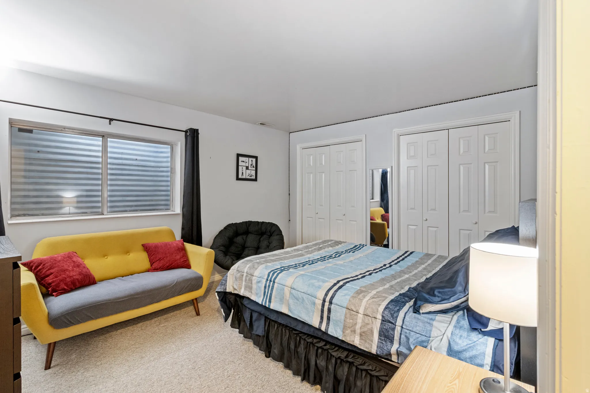 Carpeted room with a horizontal sliding window, two white bi-fold closet doors, and light-colored walls