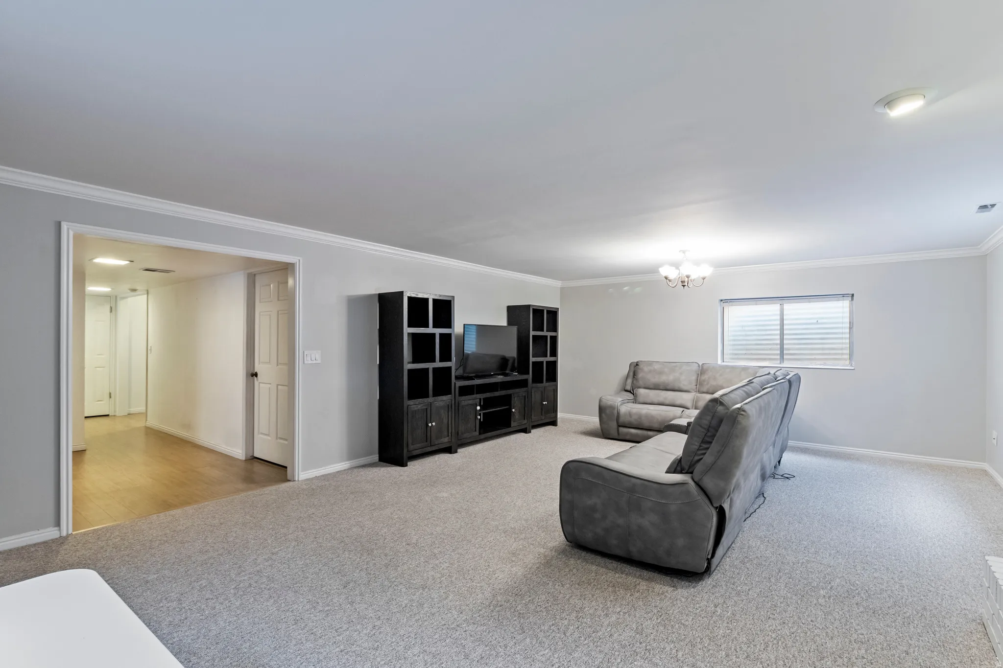 Spacious room featuring light gray walls, crown molding, recessed lighting, and soft gray carpeting