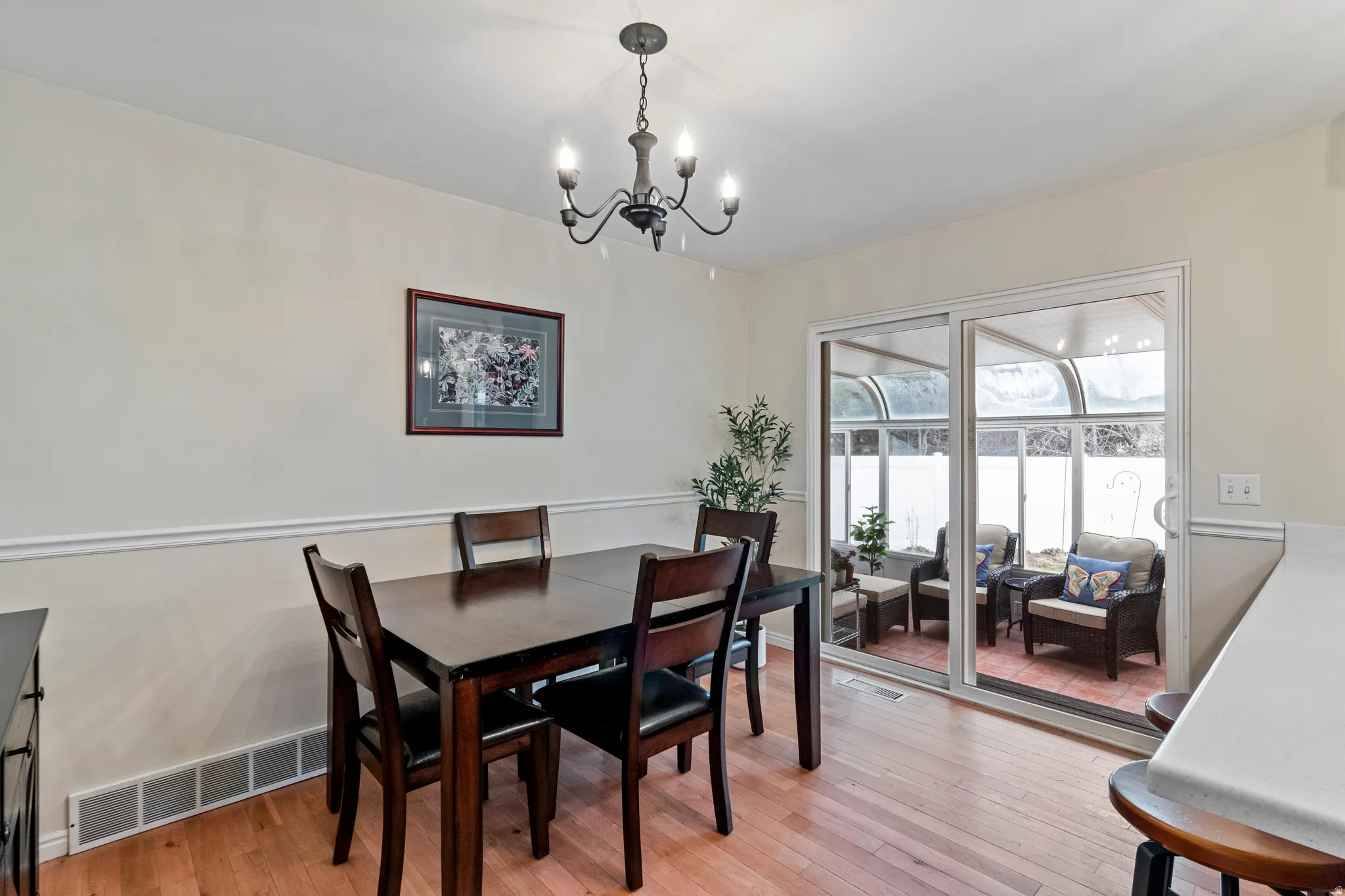 Dining area featuring wood-finish flooring, chair rail molding, and a chandelier