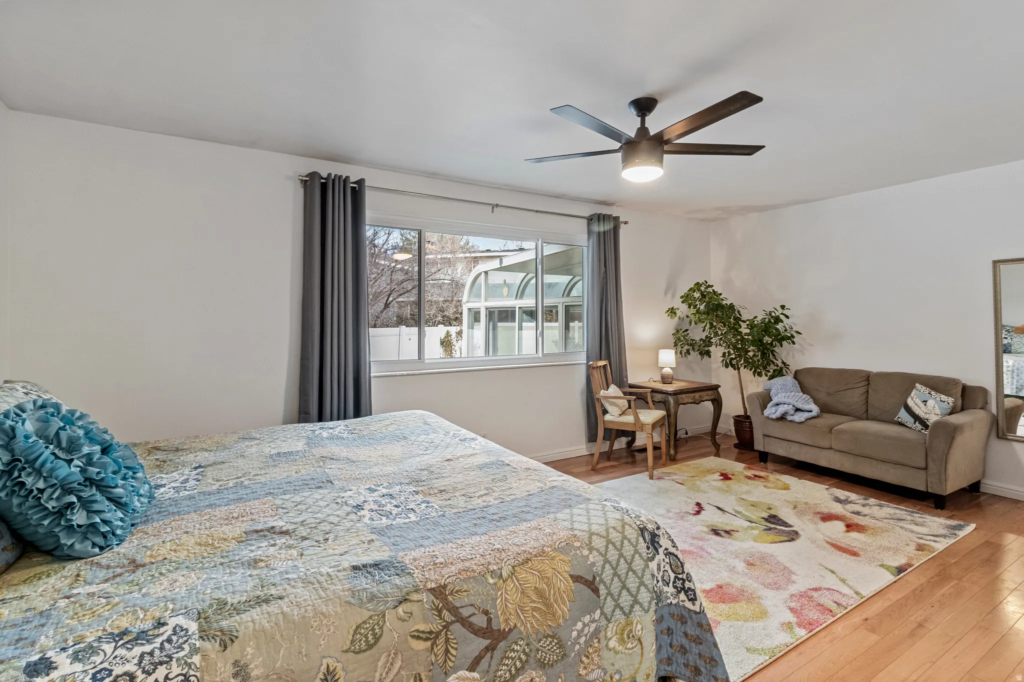 Room featuring wood-finish flooring, a contemporary ceiling fan, and a large window