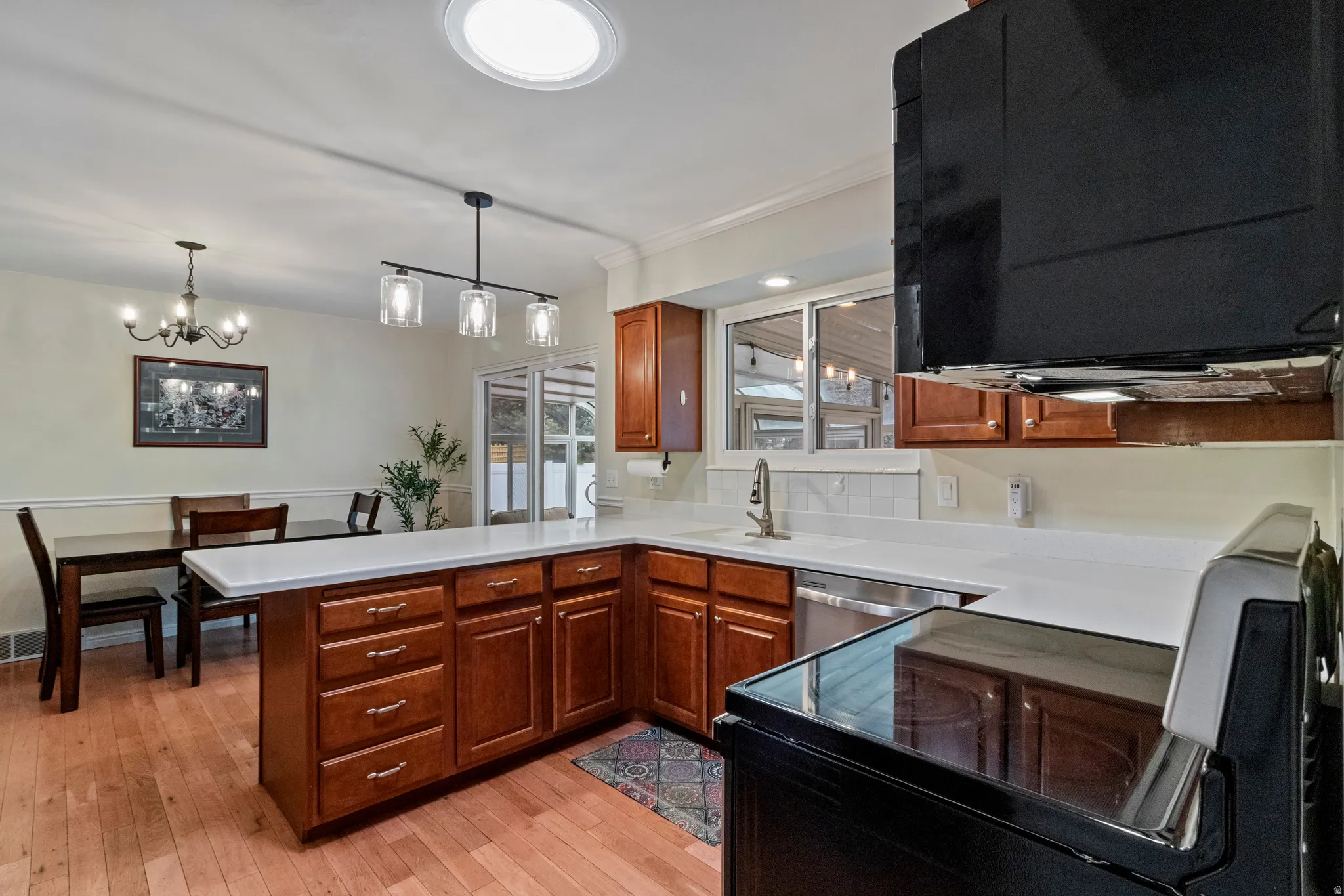 L-shaped kitchen island featuring wood cabinetry and light-colored countertops