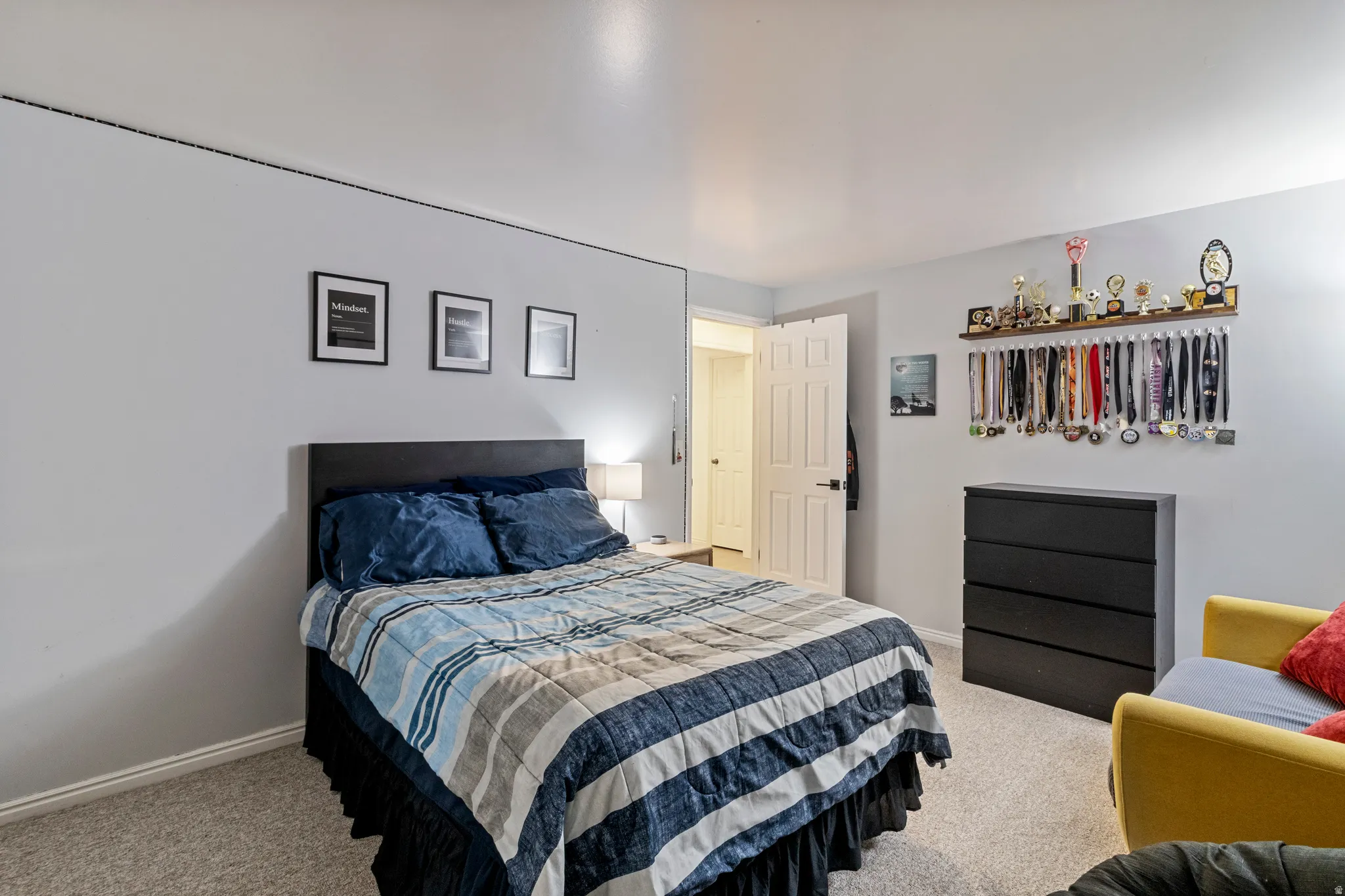 Bedroom featuring light gray walls, textured carpeting, and a built-in wall shelf