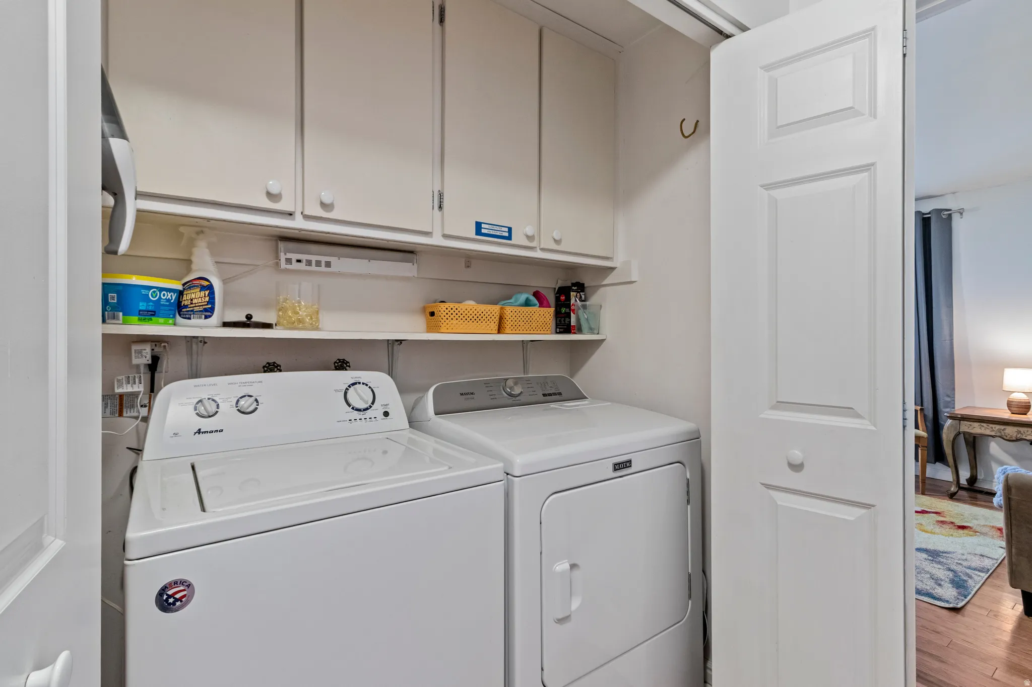 Dedicated laundry area featuring upper cabinetry, open shelving, and bifold door access
