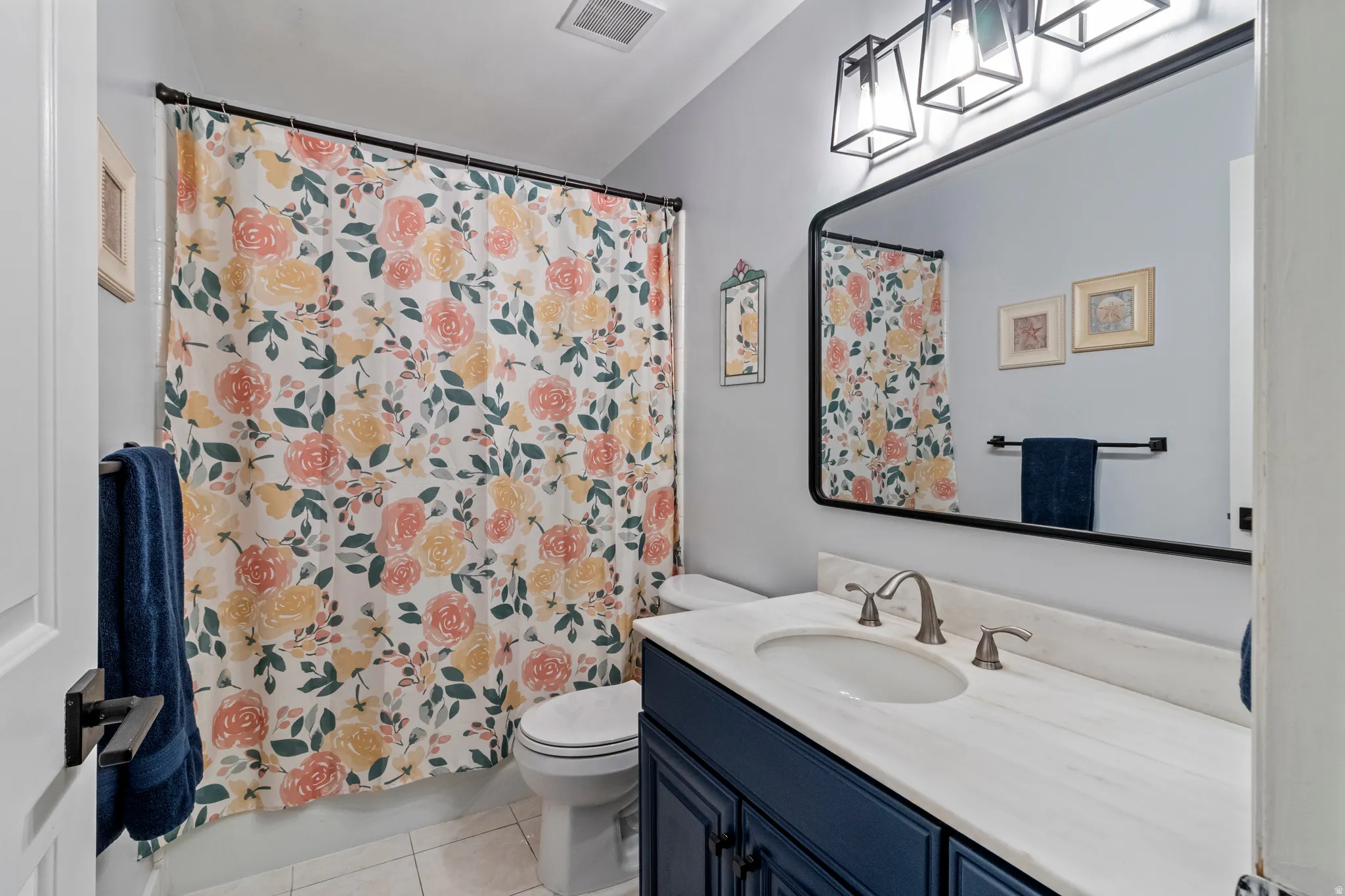 Bathroom featuring a single-sink vanity with white countertop, dark blue cabinetry, and a framed mirror