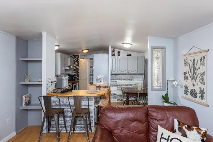 Open-concept living area featuring wood-finish flooring, built-in shelving, and a breakfast bar with a wood countertop