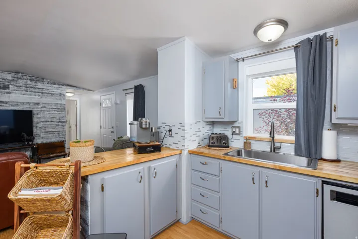 Kitchen featuring wood-finish countertops, stainless steel sink with a dark-finish faucet, and light gray cabinetry
