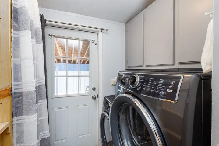 Laundry area featuring built-in cabinetry, a rear exterior door with glass panes, and wood-finish paneling
