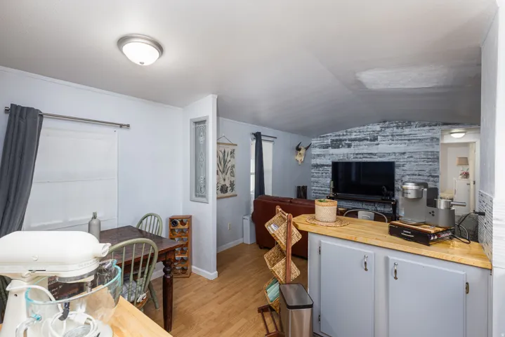 Open-concept living space featuring wood-finish flooring, a dining area with a window, and a living area with an accent wall