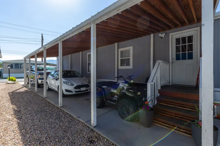 Carport with a solid roof structure and exposed wood-finish rafters