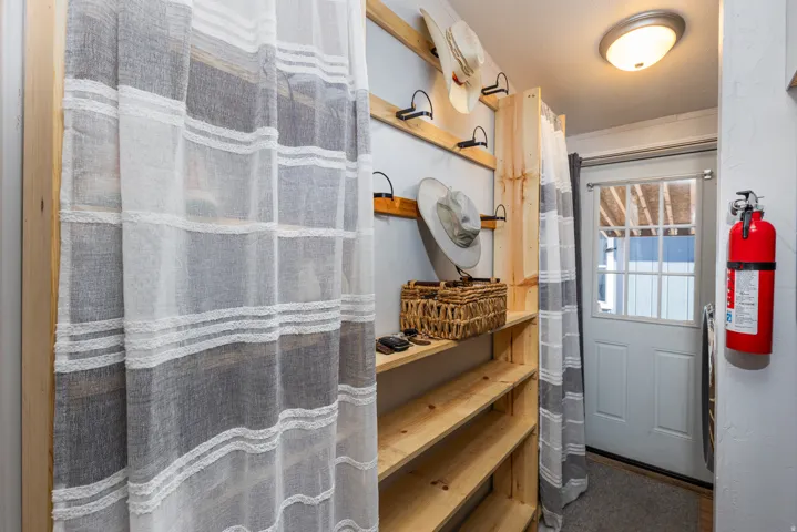 Entryway with built-in wooden shelving, wall-mounted hooks, and a paneled door with glass inserts