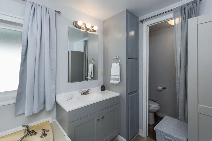Bathroom featuring a single vanity with a white countertop, brushed nickel faucet, and a wall-mounted mirror