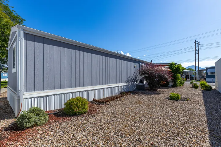 Exterior featuring vertical siding and white trim, with a gravel and mulch ground cover