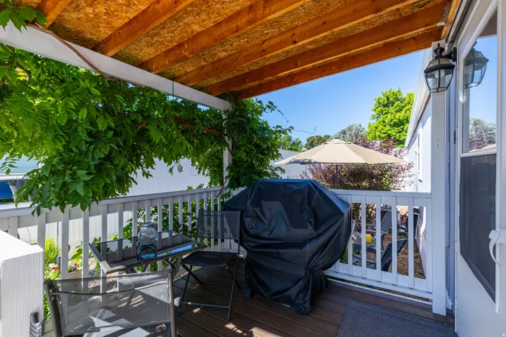 Covered outdoor patio featuring a wood-finish ceiling, white railing, and exterior wall lighting