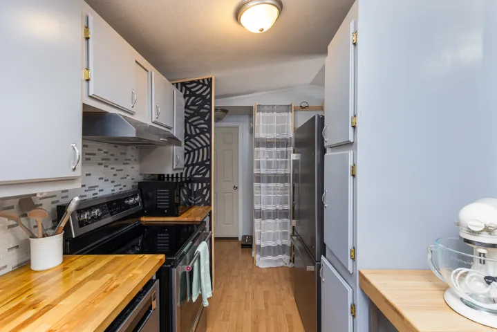Kitchen featuring light gray cabinetry, wood-finish countertops, and a tiled backsplash