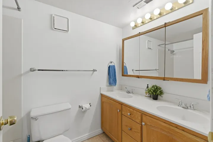 Dual vanity with wood-finish cabinetry, white countertops, and integrated sinks