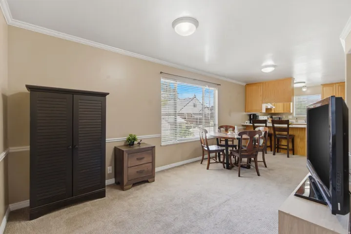 Living area featuring neutral-toned walls, crown molding, and carpet flooring