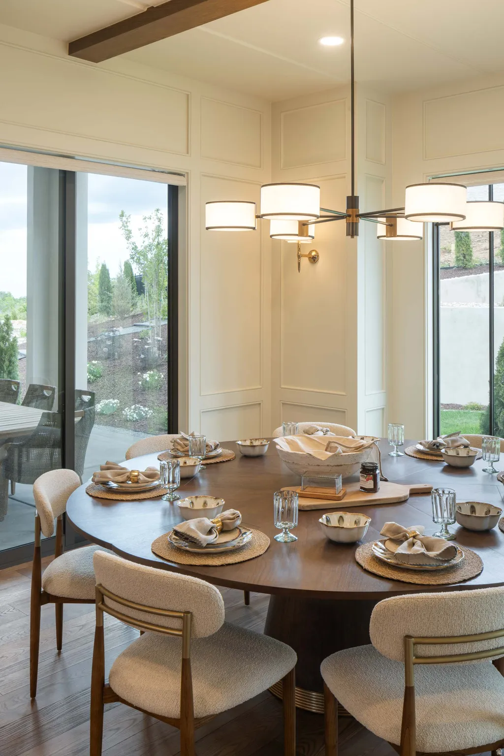 Spacious dining area featuring a dark wood-finish round table, upholstered seating, and a modern chandelier