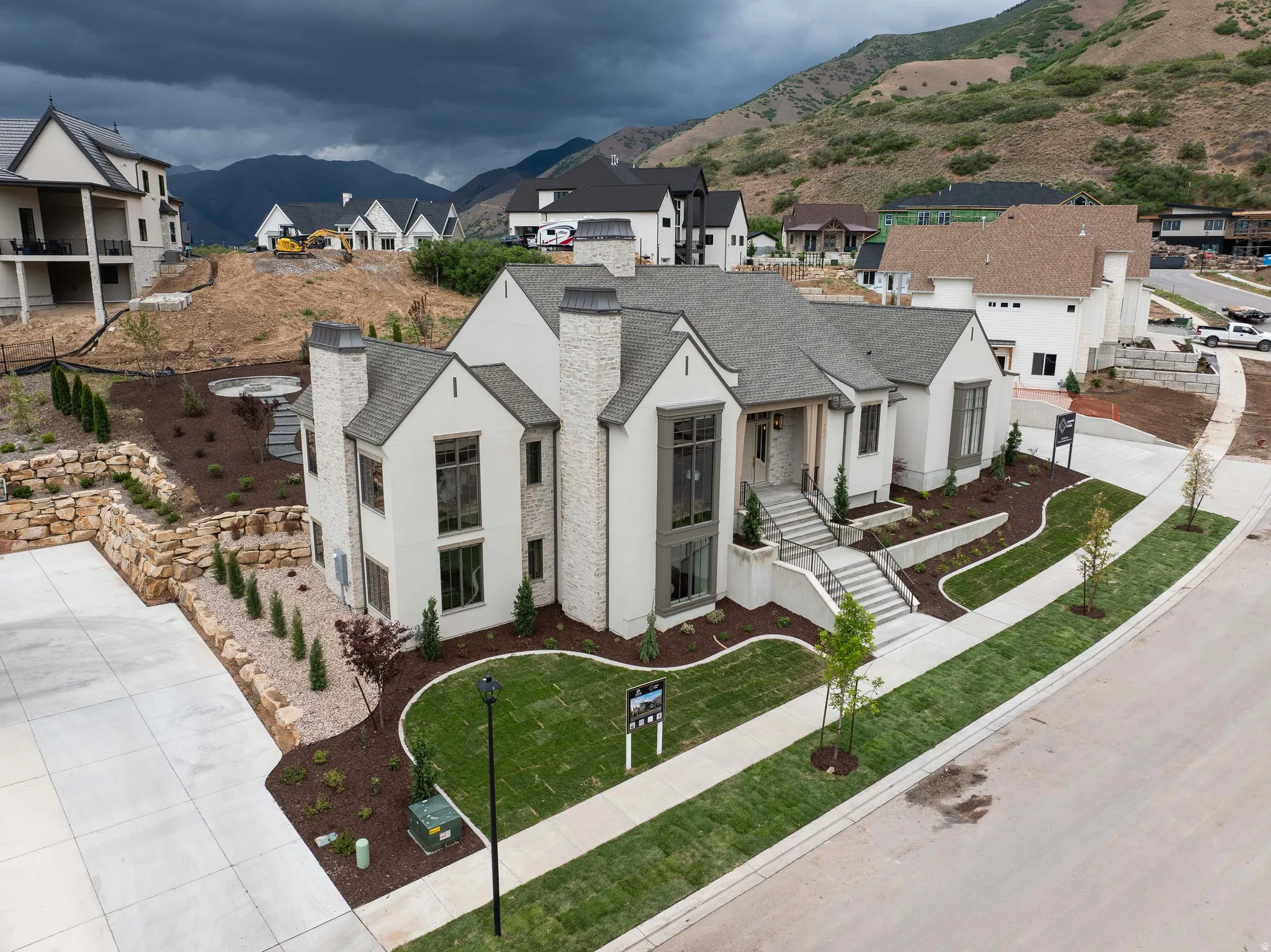 Contemporary residence with a light stucco and stone facade, featuring multiple gabled rooflines, prominent chimney structures, and large windows
