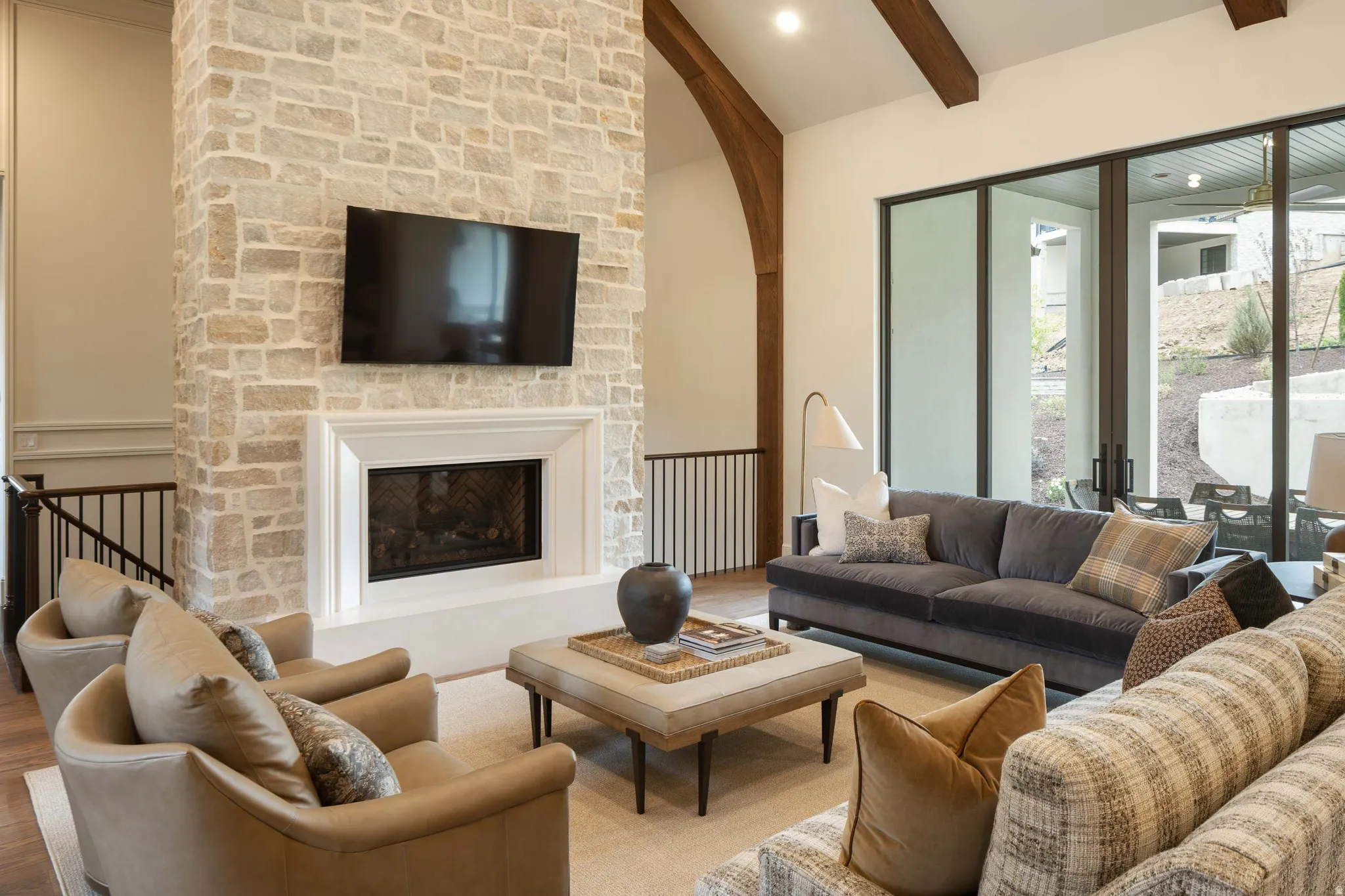 Stone-clad fireplace with a white mantel and hearth, set against a backdrop of tall ceilings with exposed wood beams