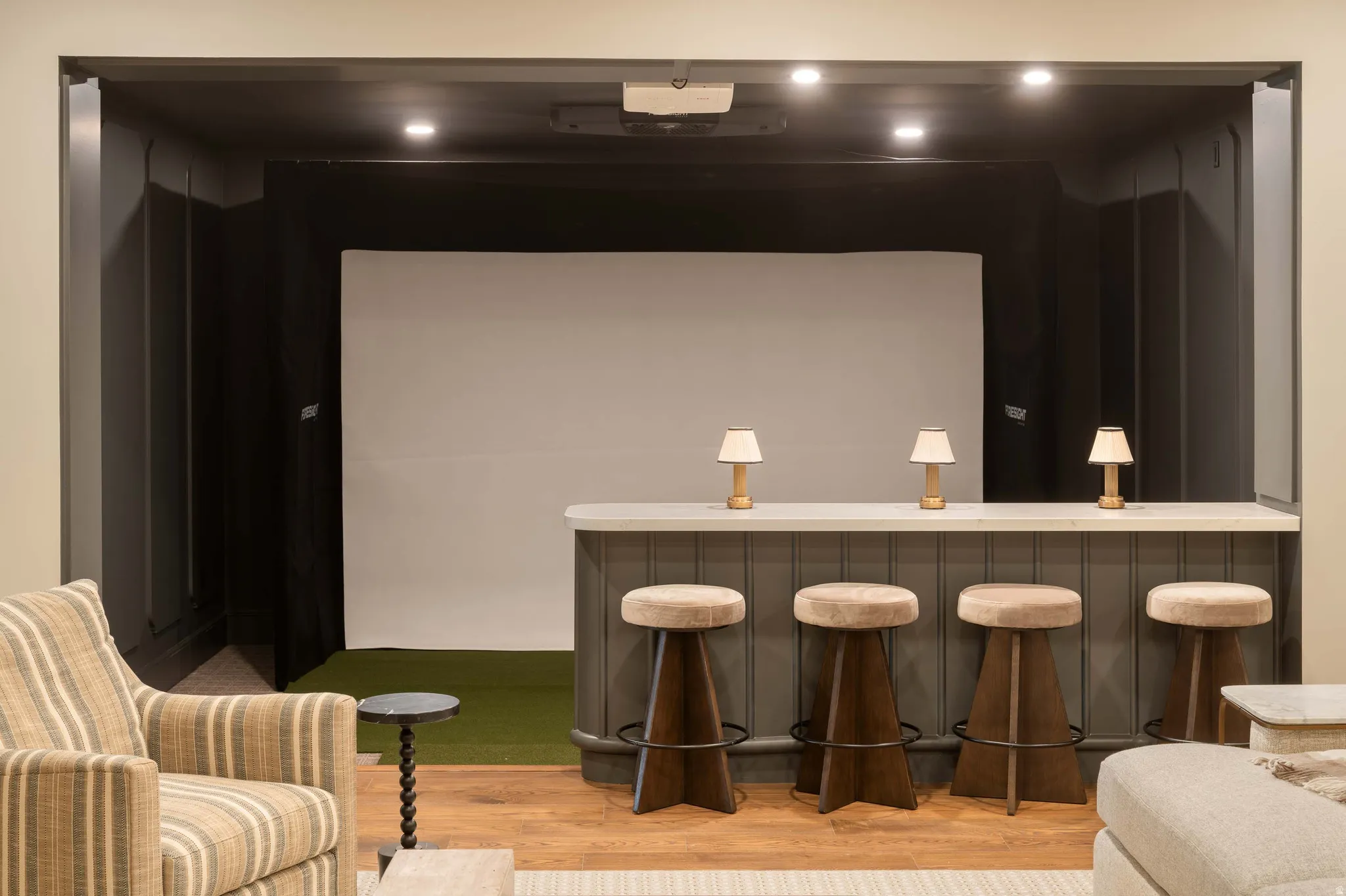 Dedicated entertainment space featuring a projection screen, recessed lighting, and a built-in bar