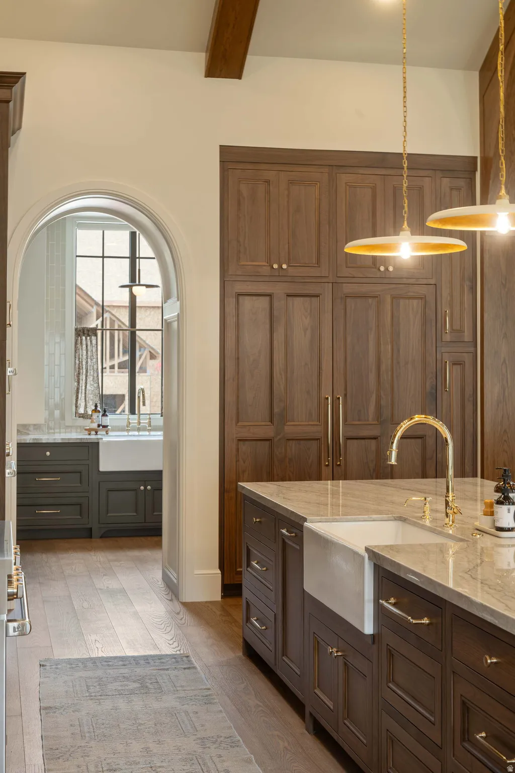 Kitchen featuring a large island with an apron-front sink, gold-toned faucet, and stone countertop