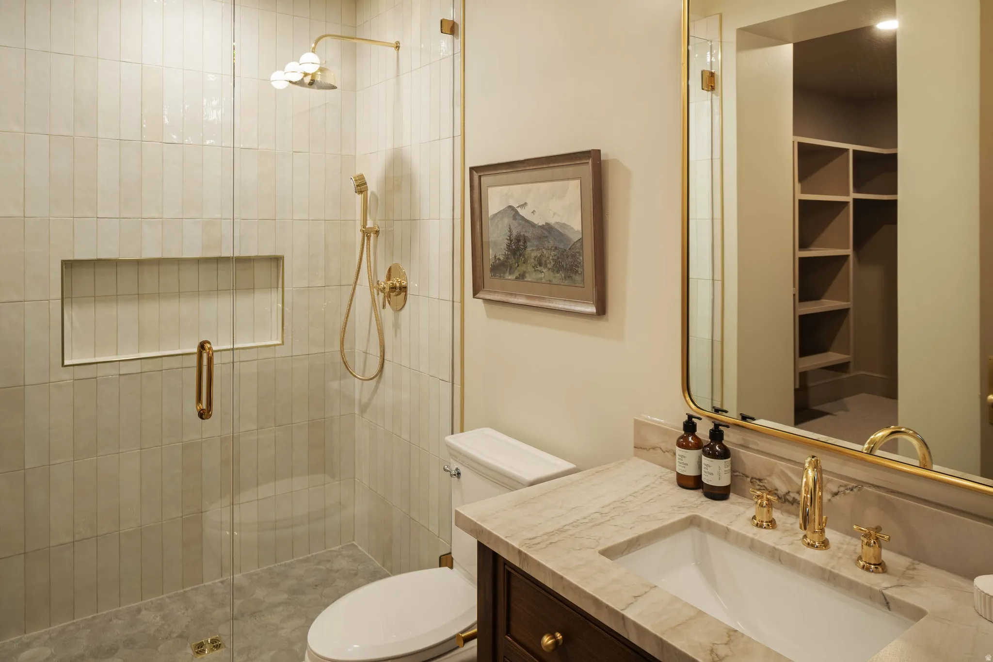 Bathroom featuring a glass-enclosed shower with vertical tile work and a built-in niche