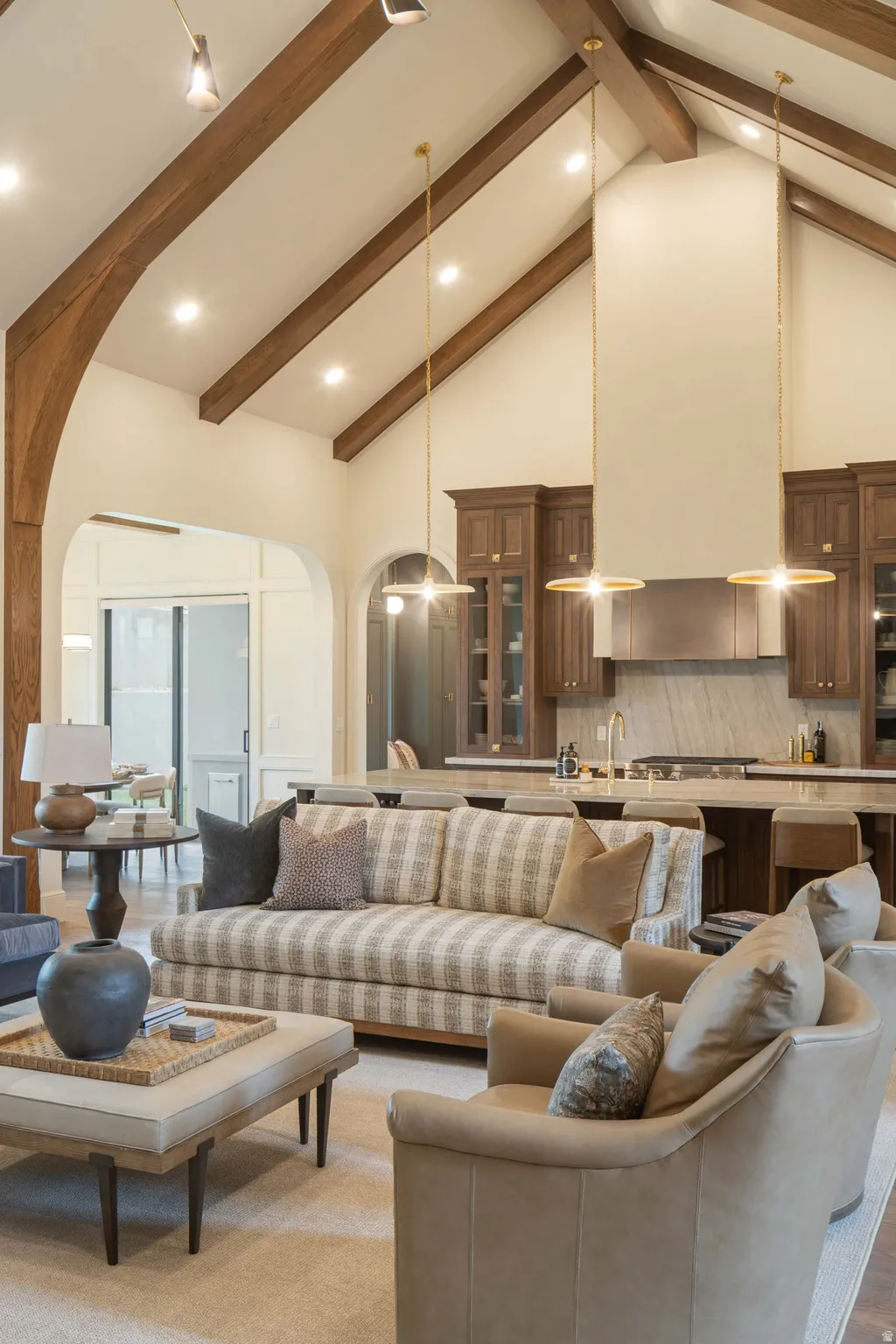 Vaulted ceiling with exposed wood beams, recessed lighting, and a prominent kitchen island with pendant lighting