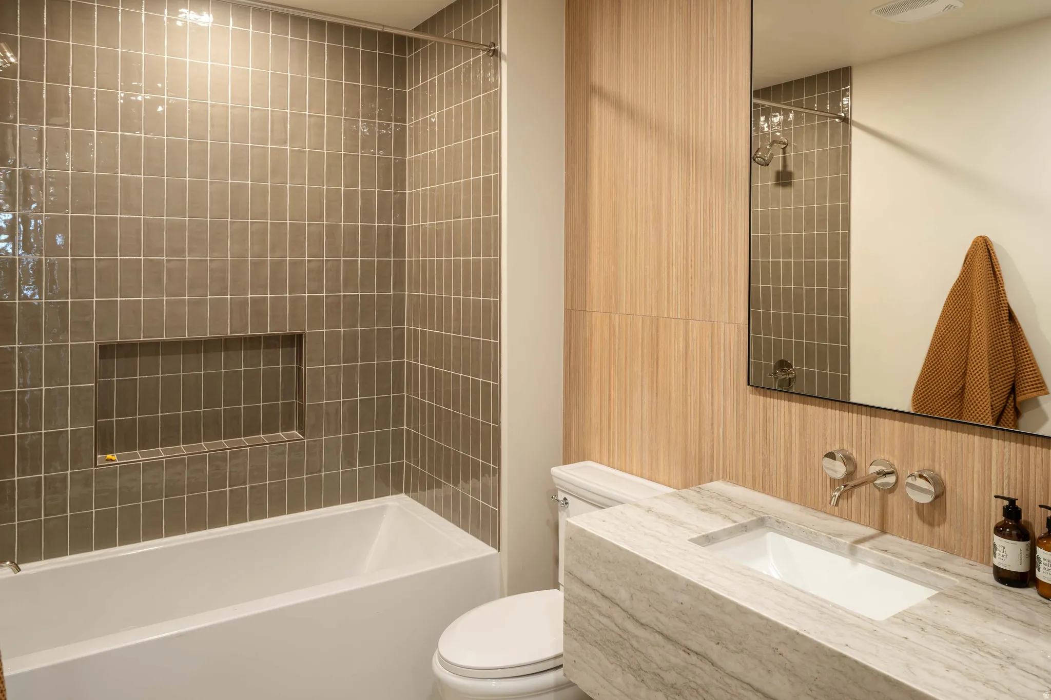 Contemporary bathroom featuring a floating vanity with integrated sink, wall-mounted polished chrome faucet, and a large mirror