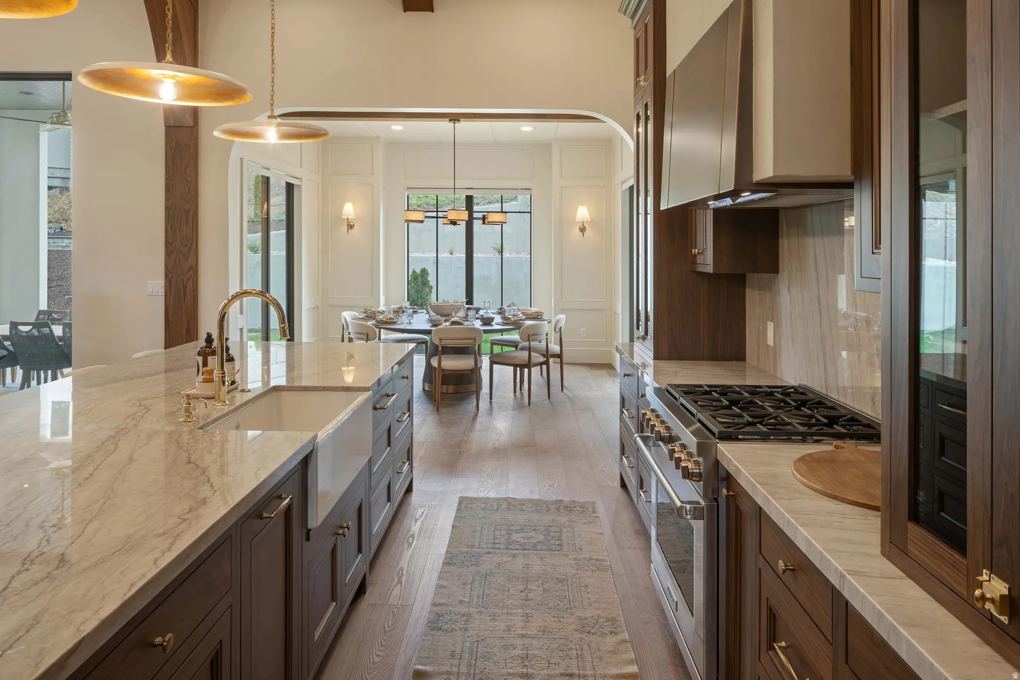 Gourmet kitchen featuring a farmhouse sink, stainless steel range with matching hood, custom dark wood cabinetry, and light-toned countertops